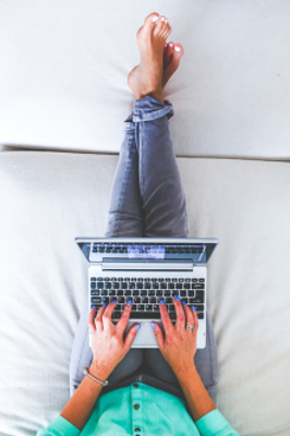 A woman sits on a couch with her laptop
