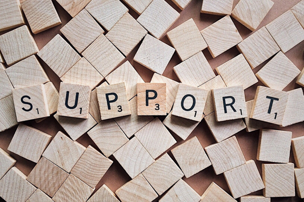 The word Support spelled out in Scrabble tiles