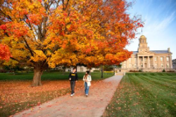 Two students walk on a university campus in the fall