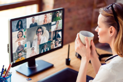 A woman holds a mug while on a video call