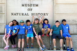 A group of children pose in front of a sign that says Museum of Natural History