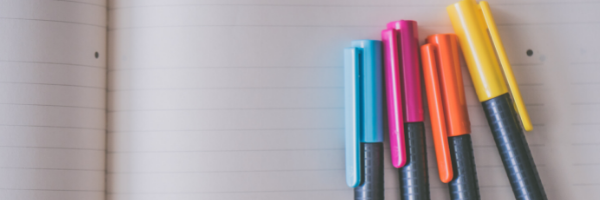 Colorful pens lined up on notebook paper